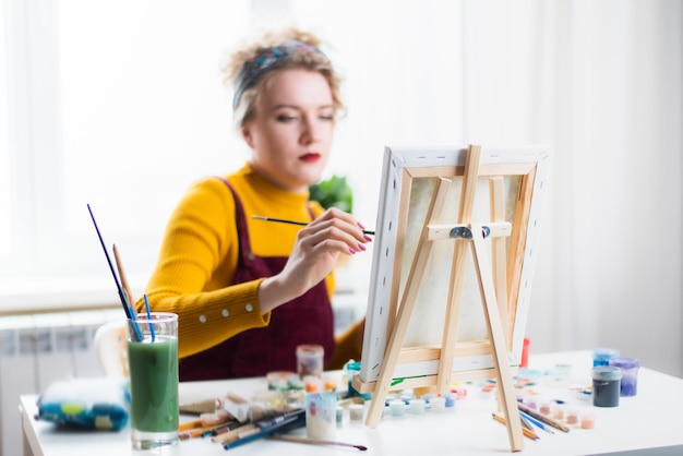 Artista de mulher bonita pinta sobre tela em casa