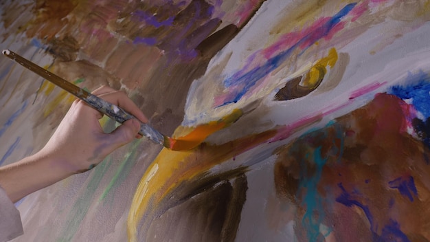 Artista diseñador dibuja un águila en la pared Artesano decorador pinta un cuadro con óleo acrílico Pintor vestido con una capa de pintura Interior Aspecto cinemático de magia oscura