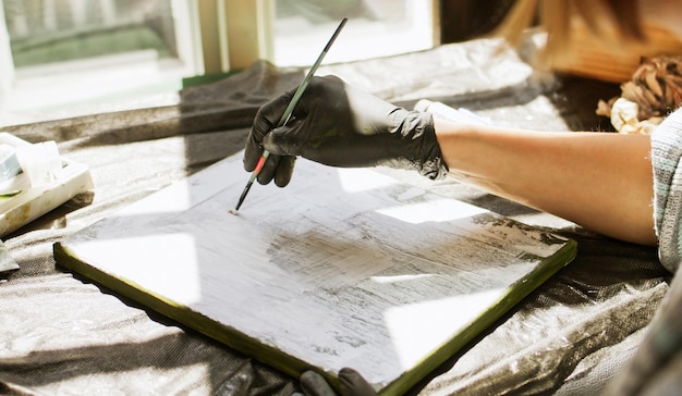 Foto artista em estúdio pinta um quadro com tintas a óleo brancas e um pincel, prepara a tela.