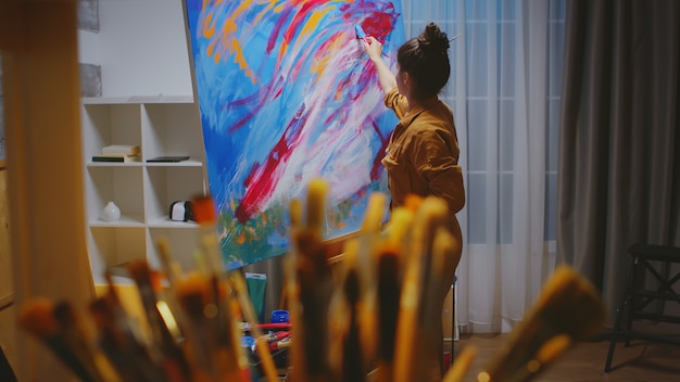 Artista escolhendo o pincel certo no estúdio de arte para sua obra-prima.