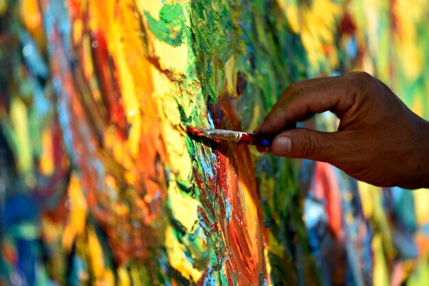 Un artista está dibujando con un pincel en un tablero colorido