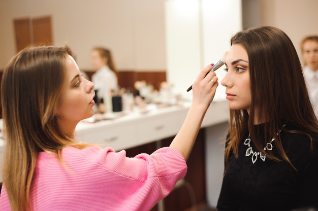 Artista fazendo maquiagem profissional de jovem.