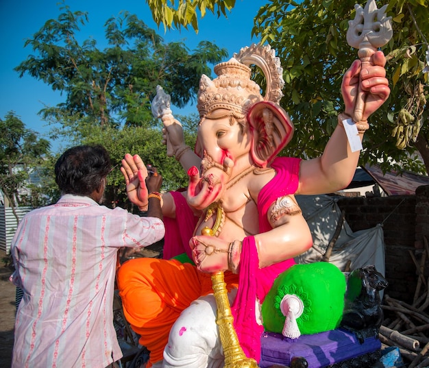 Artista fazendo uma estátua e dá os retoques finais em um ídolo do deus hindu lord ganesha em uma oficina de artista para o festival ganesha