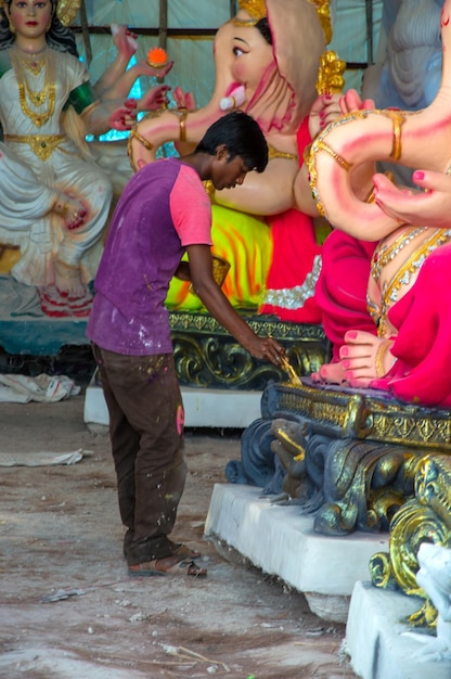 Artista fazendo uma estátua e dá os retoques finais em um ídolo do deus hindu Lord Ganesha em uma oficina de artista para o festival Ganesha