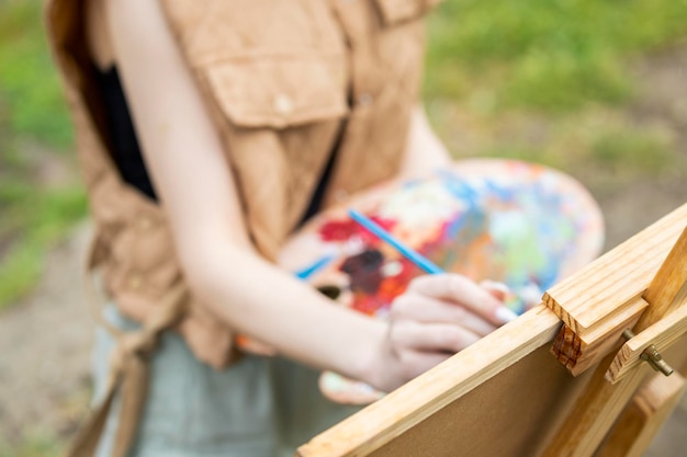 La artista femenina está pintando en el parque.