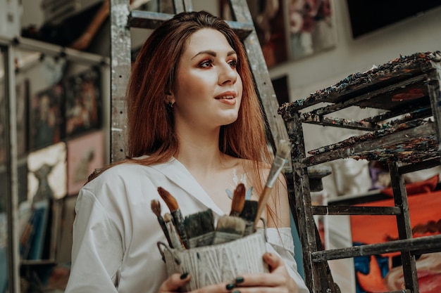 Foto artista femenina mano sujetando el pincel en el taller de arte