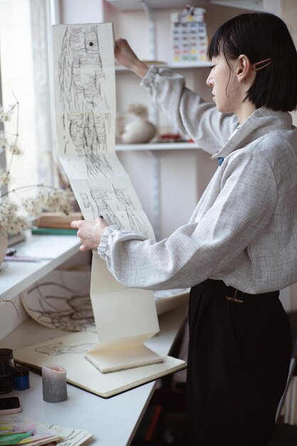 Artista femenina mira su trabajo dibujando con pluma y tinta negra Pintura gráfica Creación de arte moderno