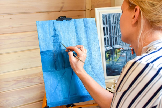 Artista femenina pinta un cuadro sobre lienzo en casa con pinturas al óleo en casa