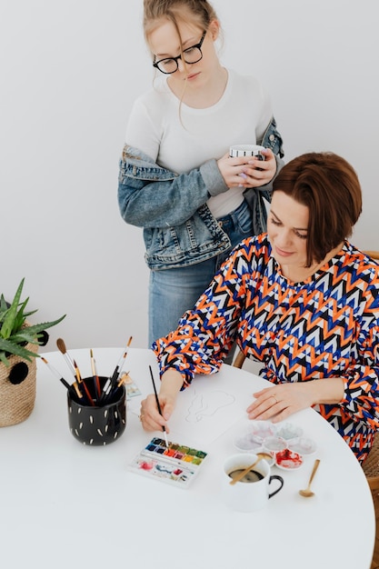 Artista feminina pintando enquanto a filha está assistindo