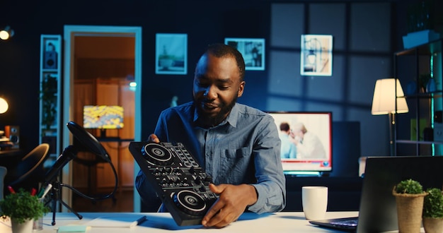 Artista filmando tutorial de mezcla de DJ mostrando ejemplos de muestreo en el controlador de sonido a la audiencia Estrella viral de Internet mostrando equipo musical moderno a los suscriptores en el estudio en casa