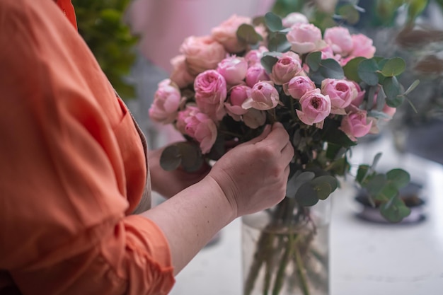 Artista floral profesional que elabora cuidadosamente un impresionante estudio de diseño floral de arreglos de rosas rosadas