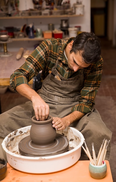 Artista hace alfarería de barro en una rueca.