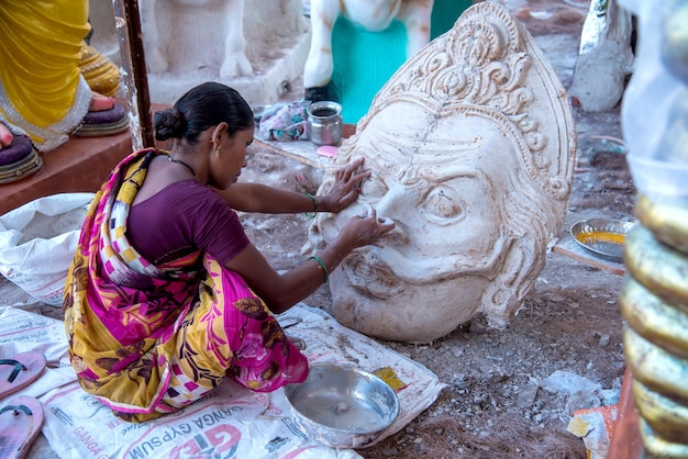 Artista haciendo una estatua y da los toques finales a un ídolo del dios hindú Lord Ganesha en un taller de artista para el festival de Ganesha