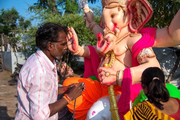 Foto artista haciendo una estatua y da los toques finales a un ídolo del dios hindú lord ganesha en un taller de artista para el festival de ganesha