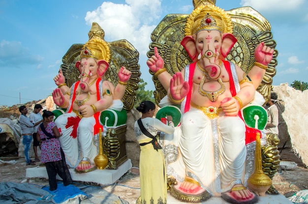 Artista haciendo una estatua y da los toques finales a un ídolo del dios hindú Lord Ganesha en un taller de artista para el festival de Ganesha