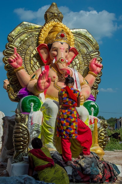 Artista haciendo una estatua y da los toques finales a un ídolo del dios hindú Lord Ganesha en un taller de artista para el festival de Ganesha