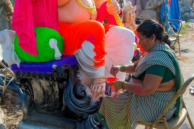 Artista haciendo una estatua y da los toques finales a un ídolo del dios hindú Lord Ganesha en un taller de artista para el festival de Ganesha