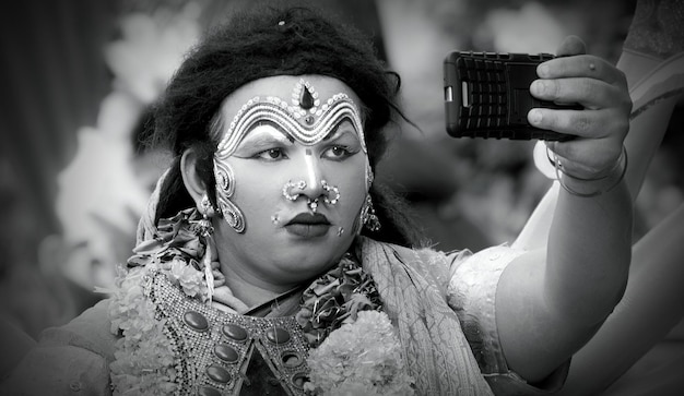 Un artista se maquilla y se toma una selfie antes de la presentación en el escenario durante un festival indio