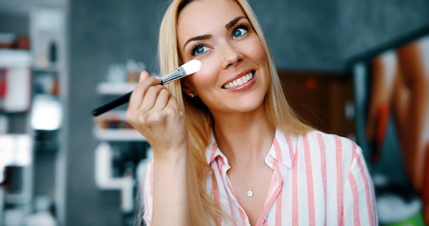 Artista de maquillaje aplica sombra de ojos. Rostro de mujer hermosa