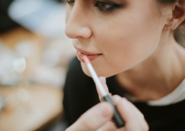 Artista de maquillaje aplicando brillo de labios en el modelo.