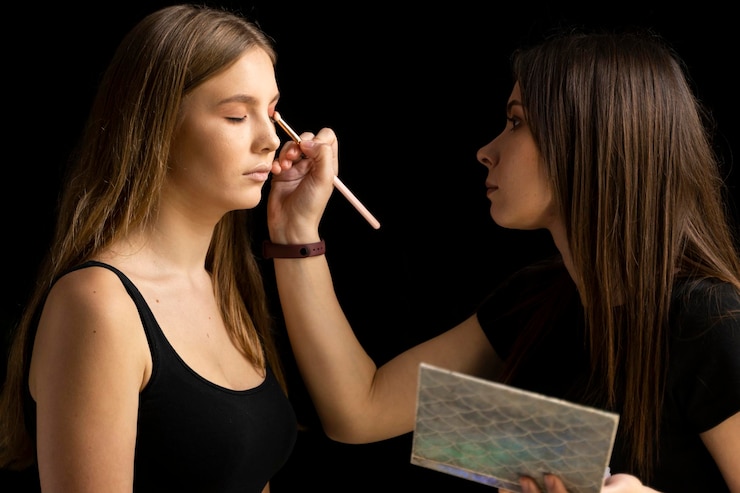 Foto artista de maquillaje aplicando maquillaje a una modelo de moda en el estudio