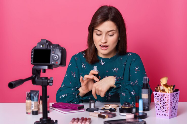 Foto el artista de maquillaje concentrado y ocupado prueba la nueva base de maquillaje frente a la cámara, usa una camisa con estampado de flores, se ve impresionado