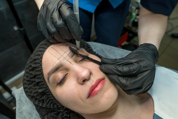 Artista de maquillaje depila las cejas en un salón de belleza Maquillaje profesional y cuidado de la piel de cosmetología