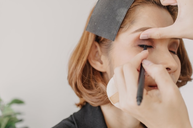 Artista de maquillaje está aplicando maquillaje en los ojos del cliente