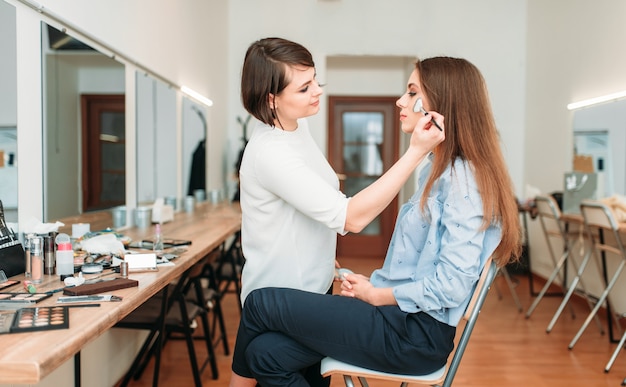Artista de maquillaje femenino trabaja con rostro de mujer