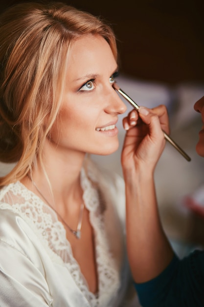 Artista de maquillaje haciendo maquillaje para joven novia hermosa