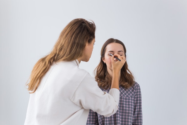 Artista de maquillaje haciendo maquillaje profesional de mujer joven