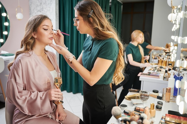 Artista de maquillaje mujer aplicando sombra de ojos en el párpado del cliente