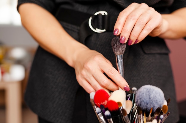 Artista de maquillaje de mujer selecciona y saca el pincel del conjunto de pinceles de maquillaje profesional