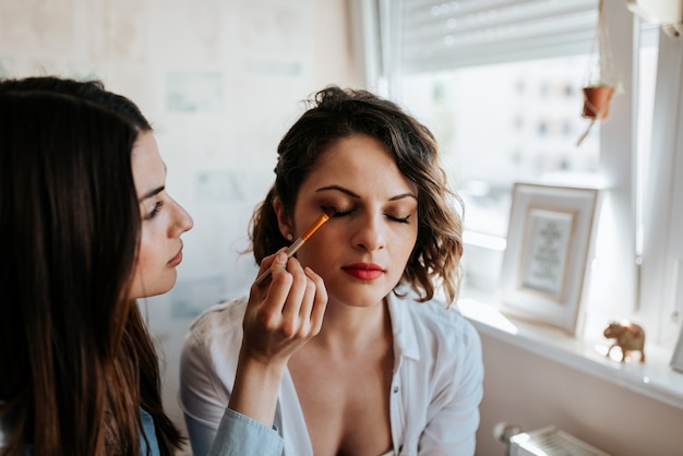 Artista de maquillaje que aplica maquillaje en una muchacha hermosa. De cerca.