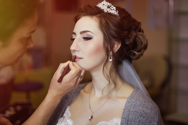 Artista de maquillaje que hace maquillaje a la novia en el día de boda.