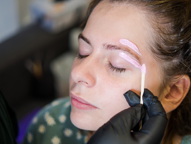 Artista de maquillaje realiza el procedimiento de depilación facial Cera derretida para depilación facial.