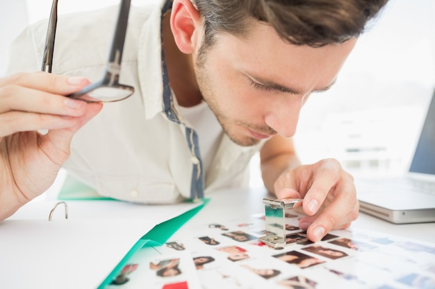 Artista masculino concentrado sentado en el escritorio con fotos