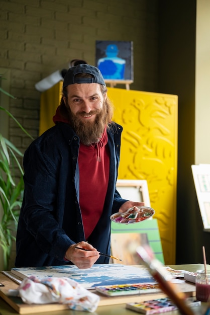 Foto artista masculino pintando con acuarela en el estudio.