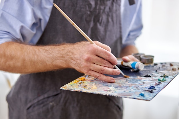 Artista mezcla colores en la paleta sosteniendo en la mano de cerca. creatividad, concepto de arte