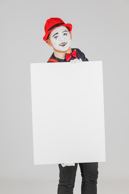 Artista MIME feliz sosteniendo una pizarra en blanco sobre un fondo blanco