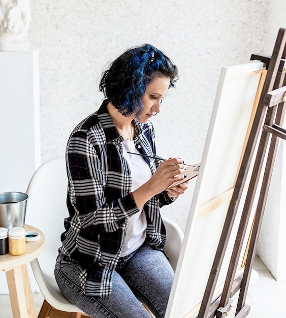 Artista mujer creativa pintando un cuadro trabajando en su estudio