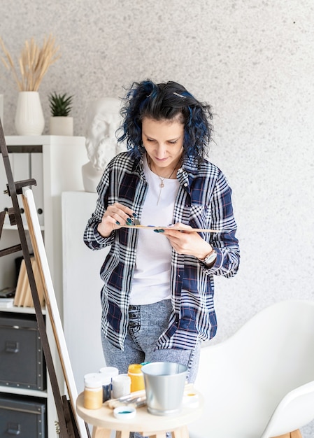 Artista mujer creativa poniendo pinturas al óleo en paleta trabajando en su estudio