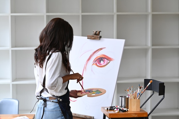 Artista mujer pintando obras de arte en su espacio de trabajo.