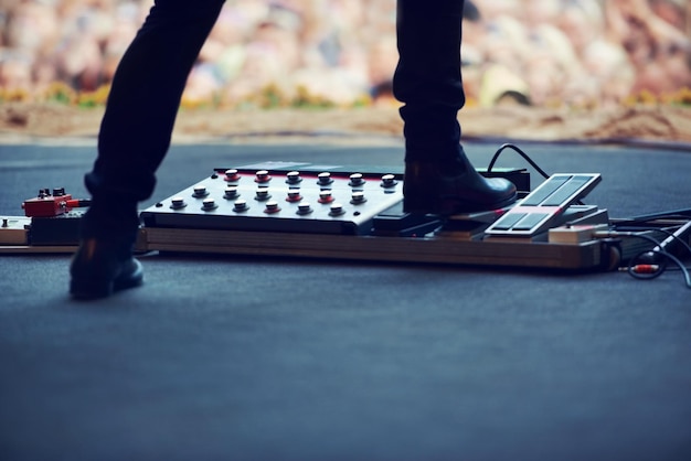 Artista no palco e pés no equipamento do instrumento em um festival de música de concerto ou evento ao vivo em Amsterdã Artista de botas e pedal em plataforma para guitarra elétrica para multidão e comunidade