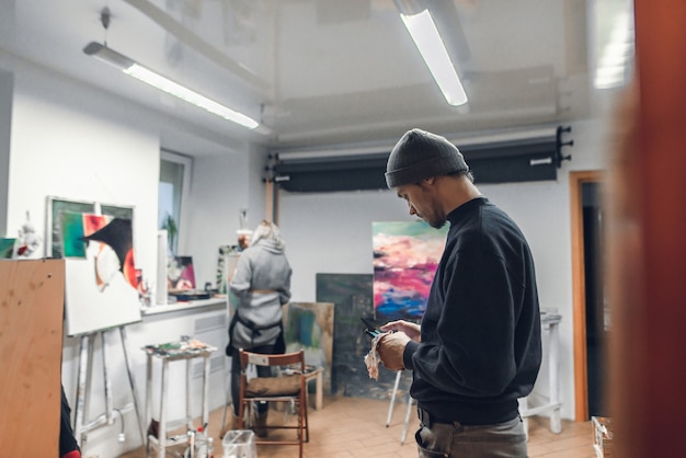 artista parado en el estudio y usando internet en un teléfono inteligente