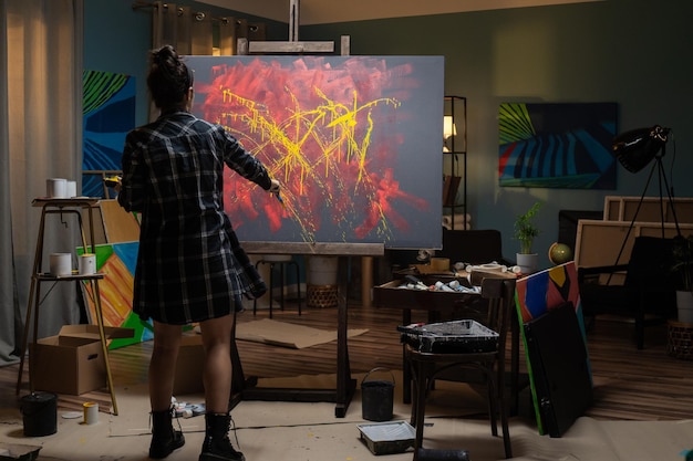 El artista pasa tiempo en el estudio pintando un cuadro abstracto en tonos amarillos y rojos.