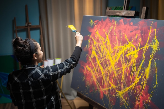 El artista pasa tiempo en el estudio pintando un cuadro abstracto en tonos amarillos y rojos.