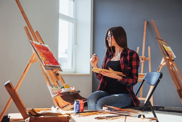 artista con un pincel en la mano y dibuja un cuadro sobre lienzo