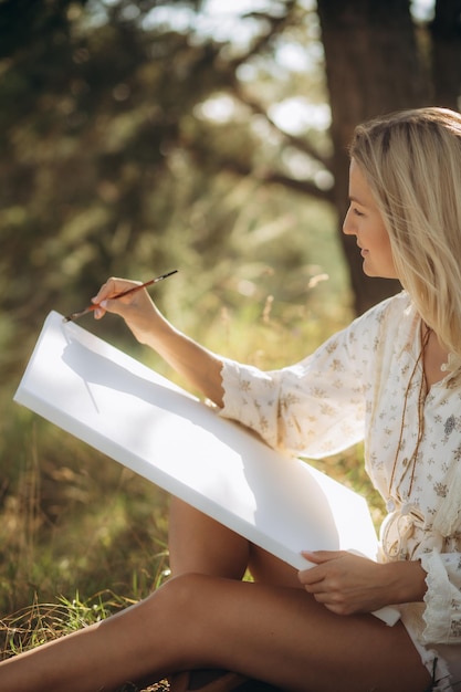 El artista pinta un cuadro al aire libre temprano en la mañana soleada Pintura en la naturaleza