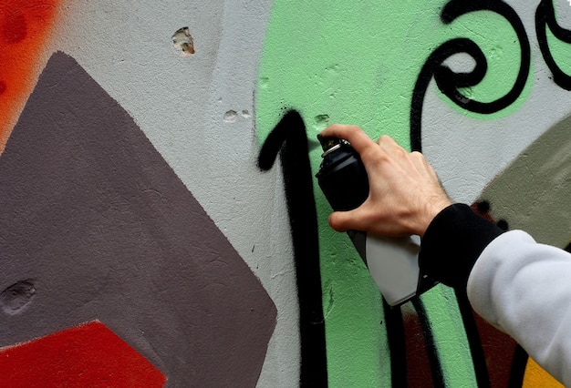 Artista pinta graffiti en un muro de hormigón.